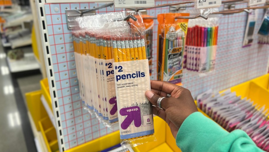 hand pulling a pack of up and up brand pencils off a target store display