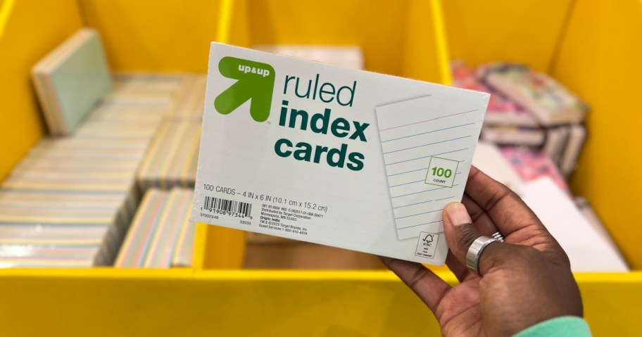 hand holding a pack of up and up ruled index cards in front of a target school supplies display