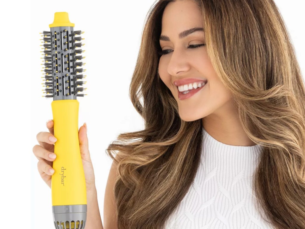woman holding Drybar dryer brush with beautiful hair