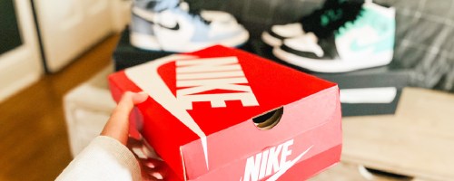 woman holding nike shoe box with nike shoes displayed in the background