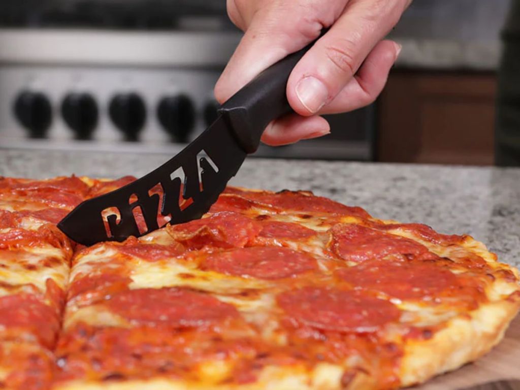 Person using the Pizza Knife to cut pizza from the Lux Decor Collection 15-Piece Stainless Steel Kitchen Knife Set