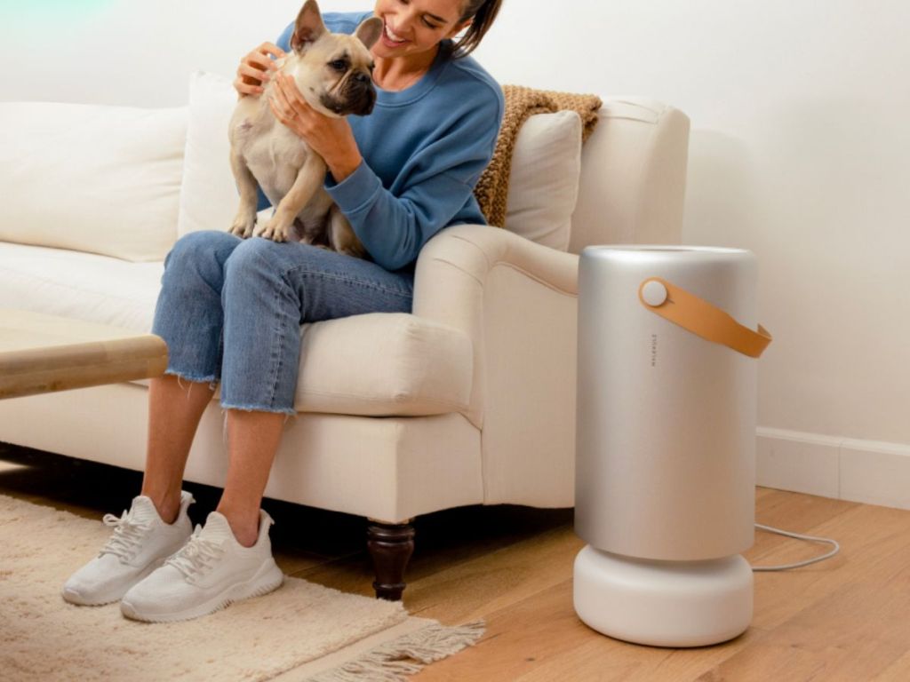 woman sitting on couch holding a dog with a Molekule Air Pro with PECO-HEPA Tri-Power Filter next to the couch