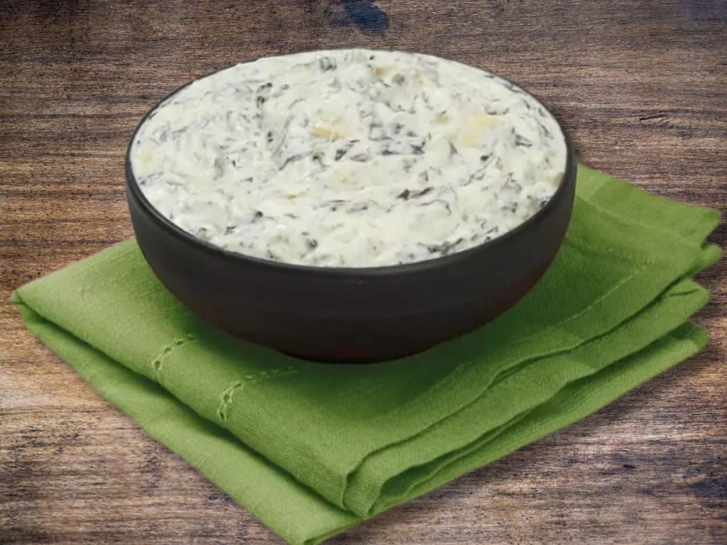 bowl of spinach dip on a green dish towel