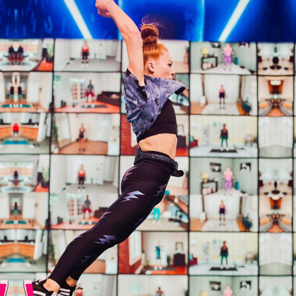 امرأة تقفز في الهواء أمام شاشات التمرين