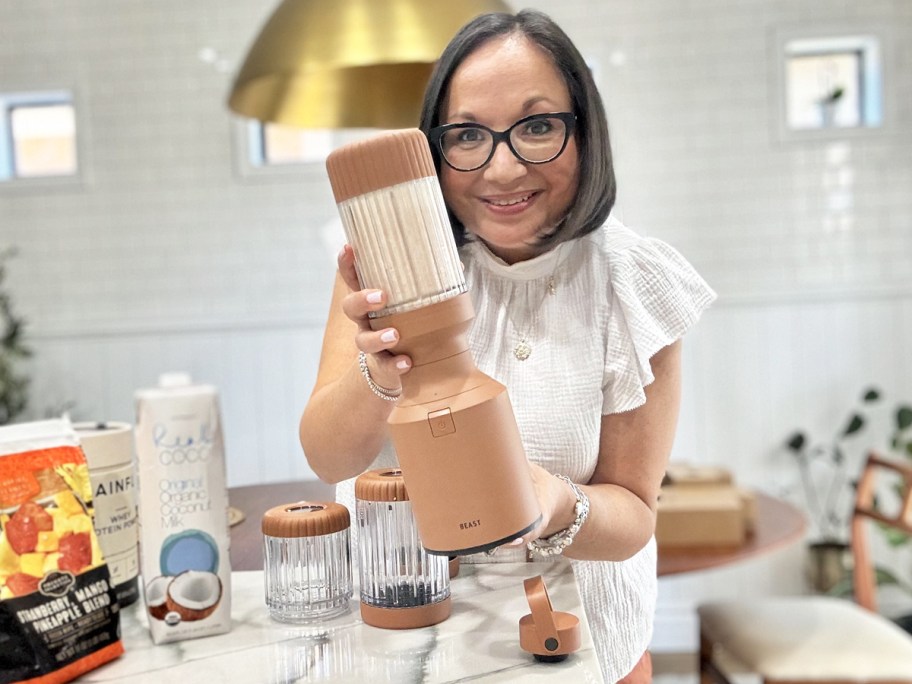 woman holding up a brand bast blender with smoothie inside