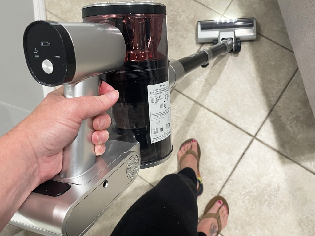 hand holding a cordless vacuum on tile foors