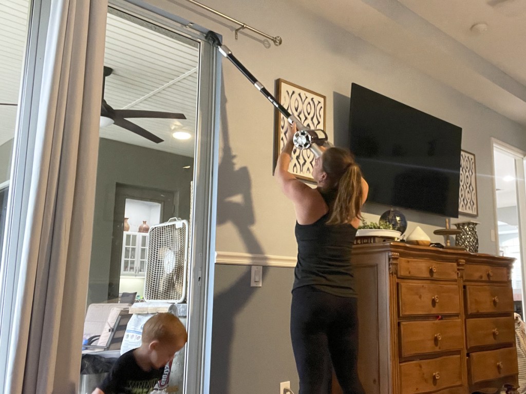 woman using cordless vacuum to clean top of doorway