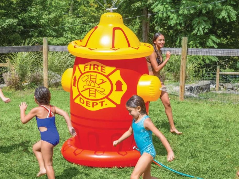 Kids playing outside with a huge inflatable fire hydrant sprinkler
