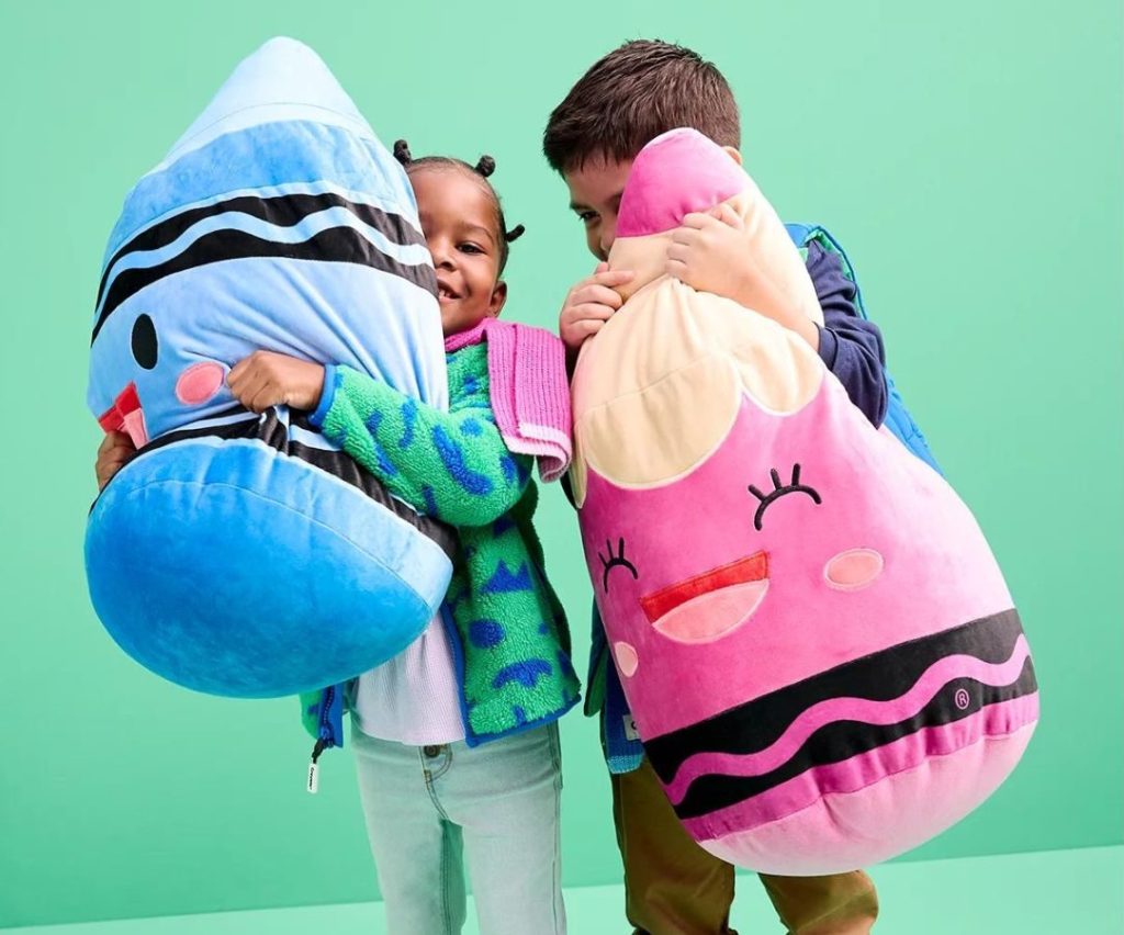 Two kids hugging giant plush Crayola Crayons from the Crayola X Kohl's Collection