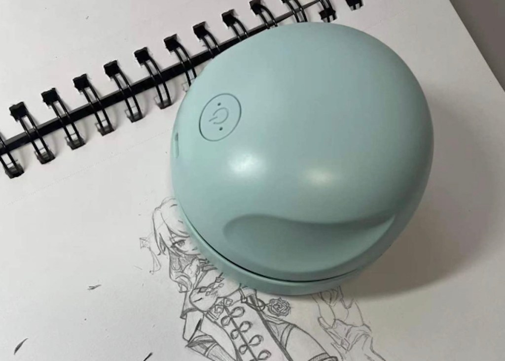 close up of blue mini desktop vacuum cleaner on spiral notebook