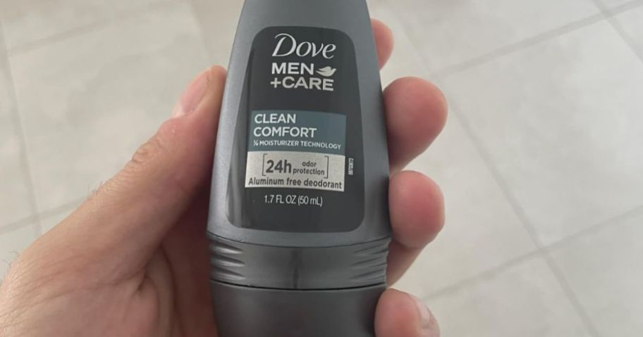 a man's hand holding a bottle of roll on deodorant