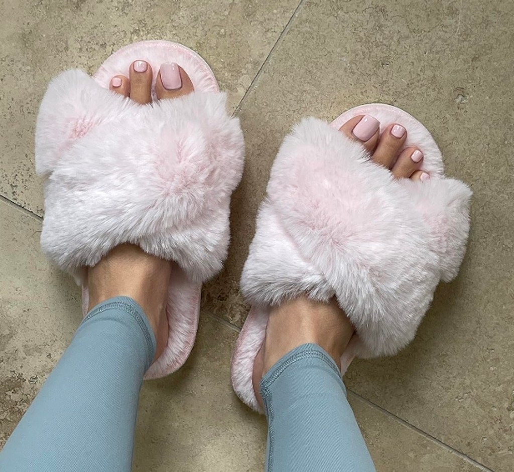 close up of pink fuzzy slippers on feet with pink toe nail polish