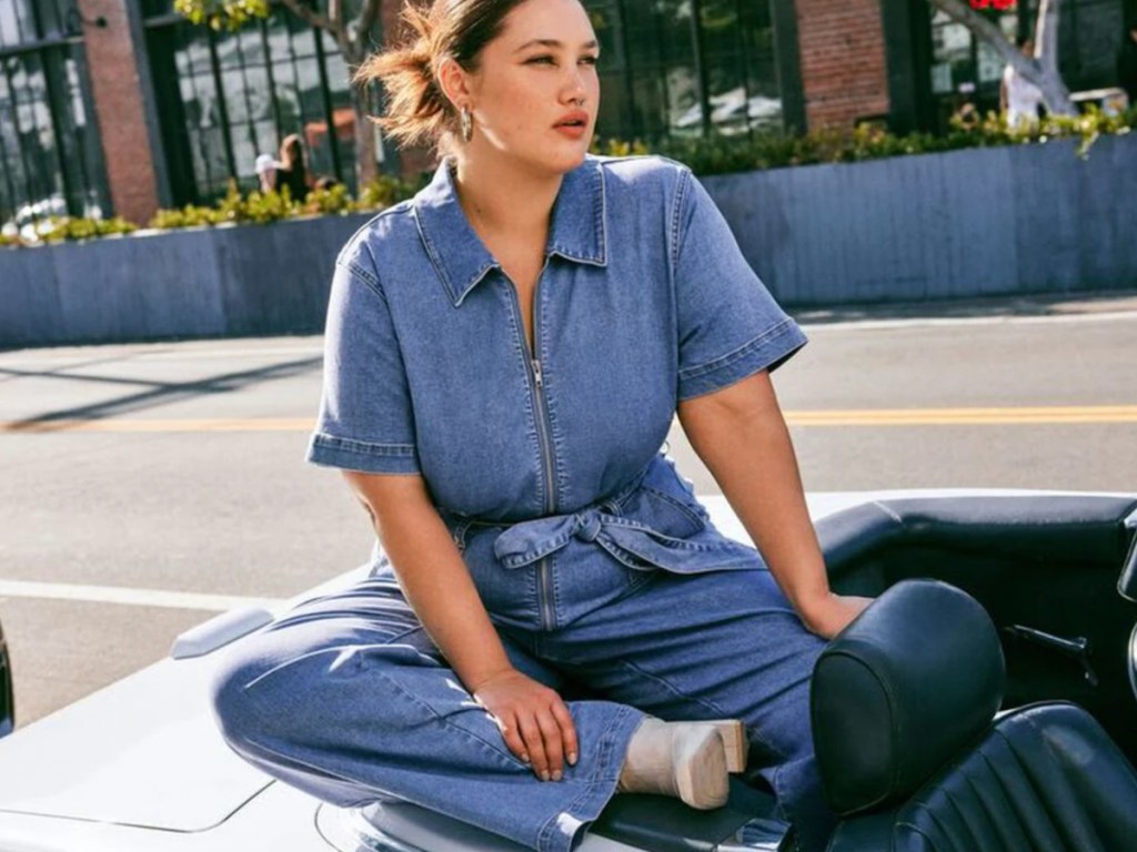 woman sitting on car in denim jumpsuit