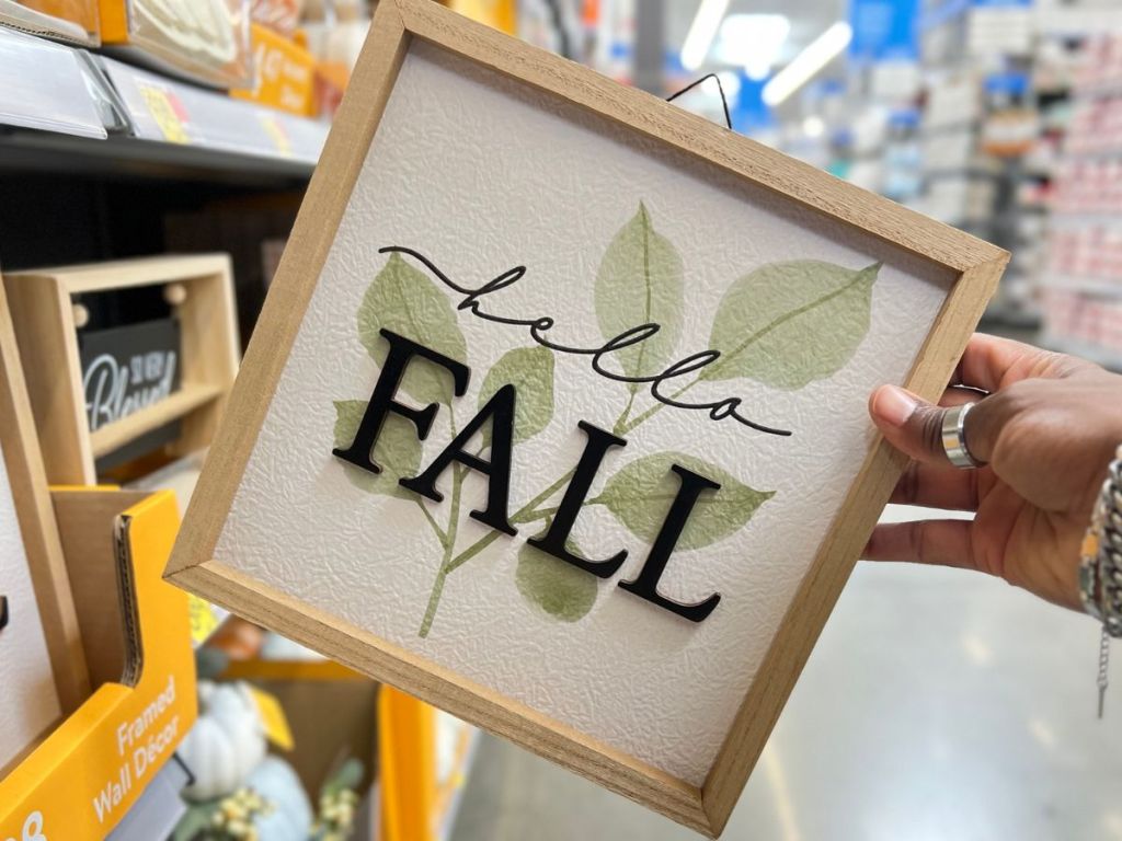 Hand holding up a Hello Fall Sign from Walmart