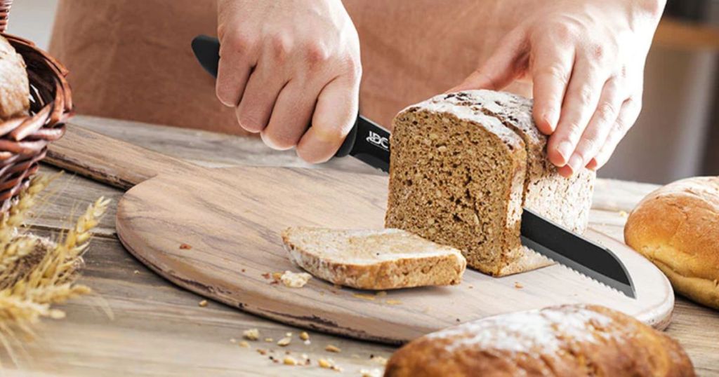 Person using the bread knife from the Lux Decor Collection 15-Piece Stainless Steel Kitchen Knife Set