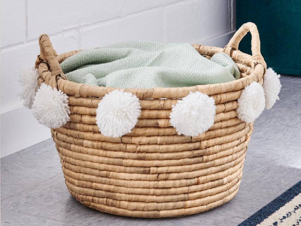 Home Depot basket with pompoms on it and blanket inside