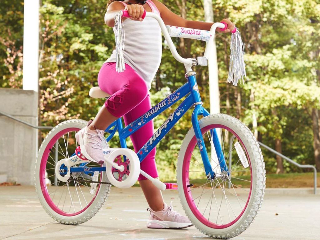 A child riding a Huffy Girls 20" Sea Star in Blue and Pink