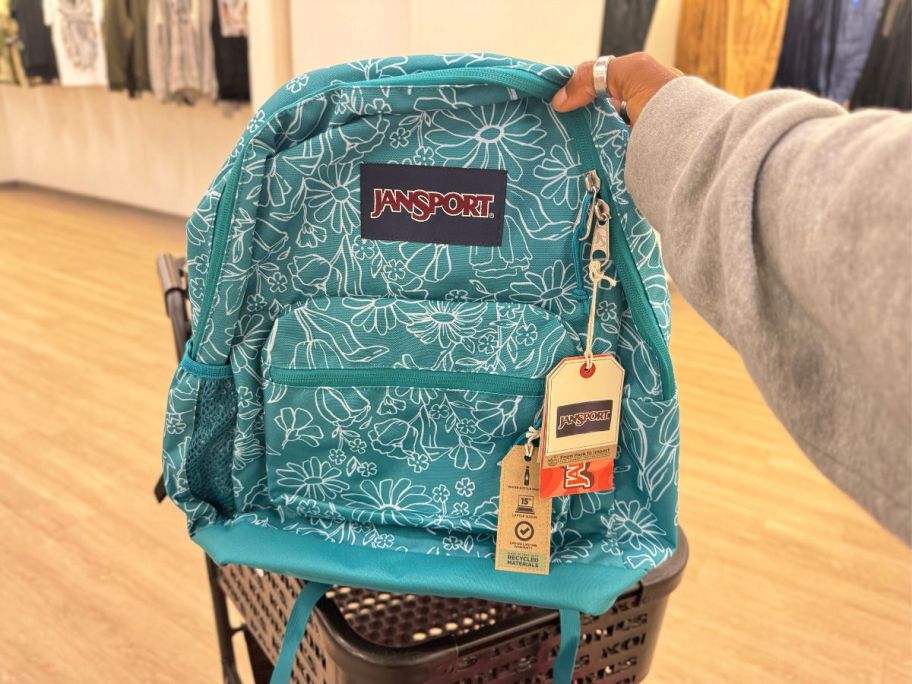 JanSport Cross Town Plus in Daisy Green being held by hand in store