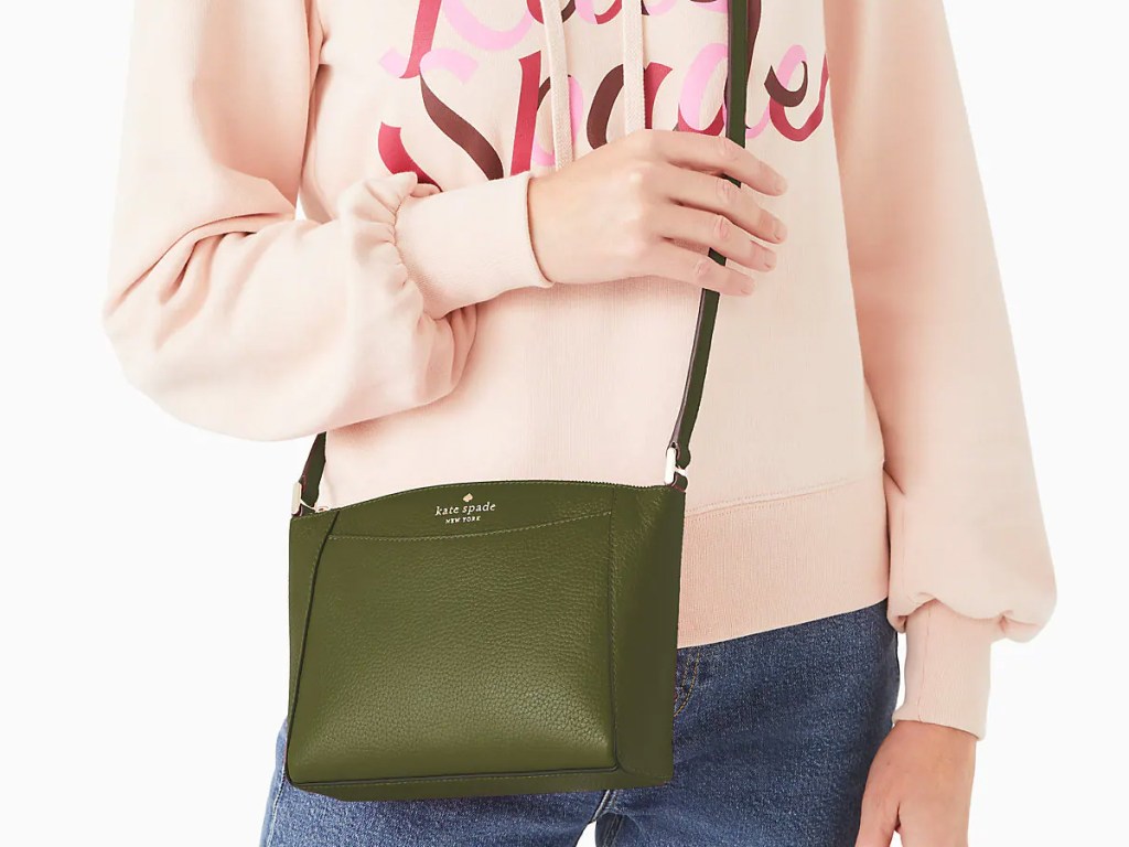 woman in pink hoodie and jeans with green crossbody bag