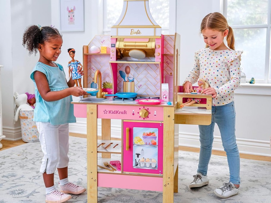 two girls playing with a barbie kidkraft kitchen