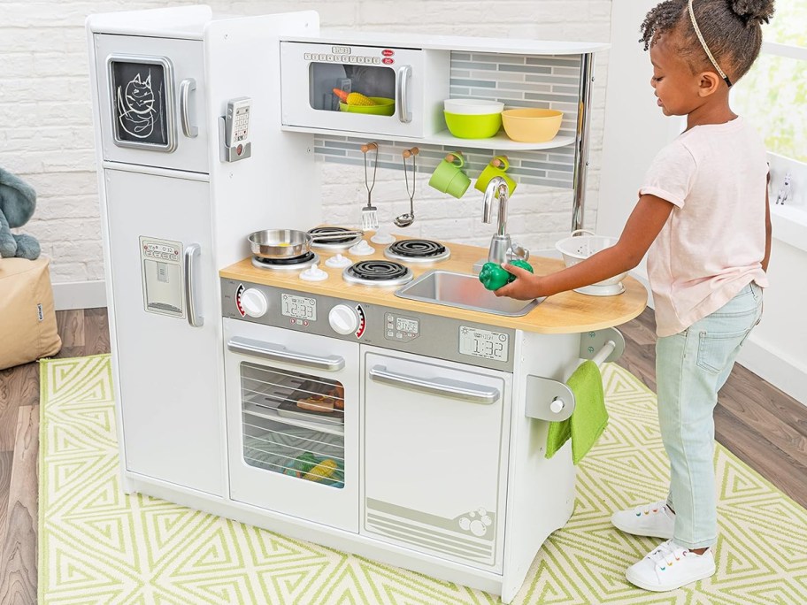 girl playing with a white kidkraft play kitchen