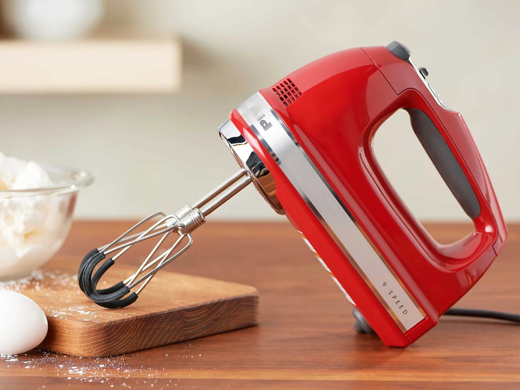 red kitchenaid hand mixer on wood table