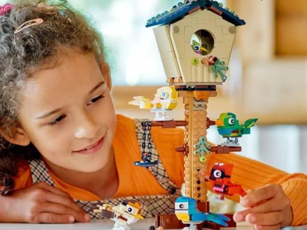 Girl playing with a LEGO birdhouse