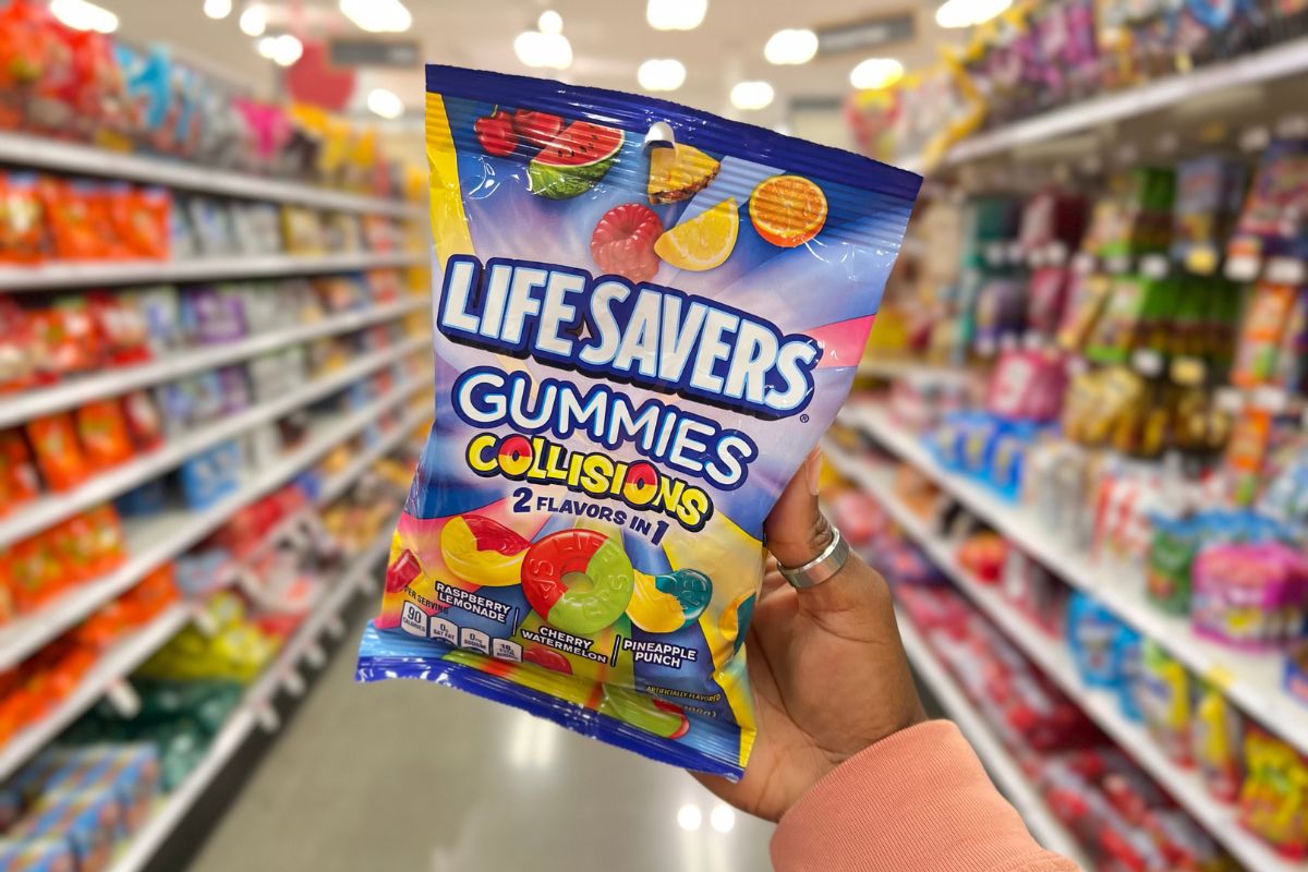 a womans hand holding up a 7 ounce bag of Life savers gummy collisions