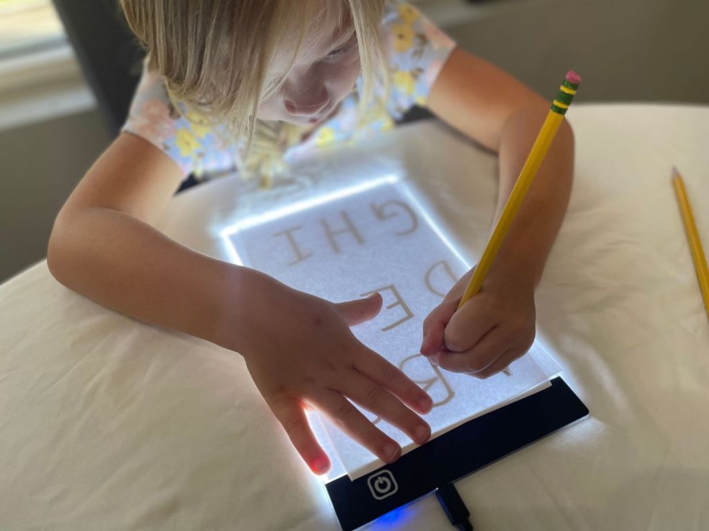 Child using an LED light board to trace letters