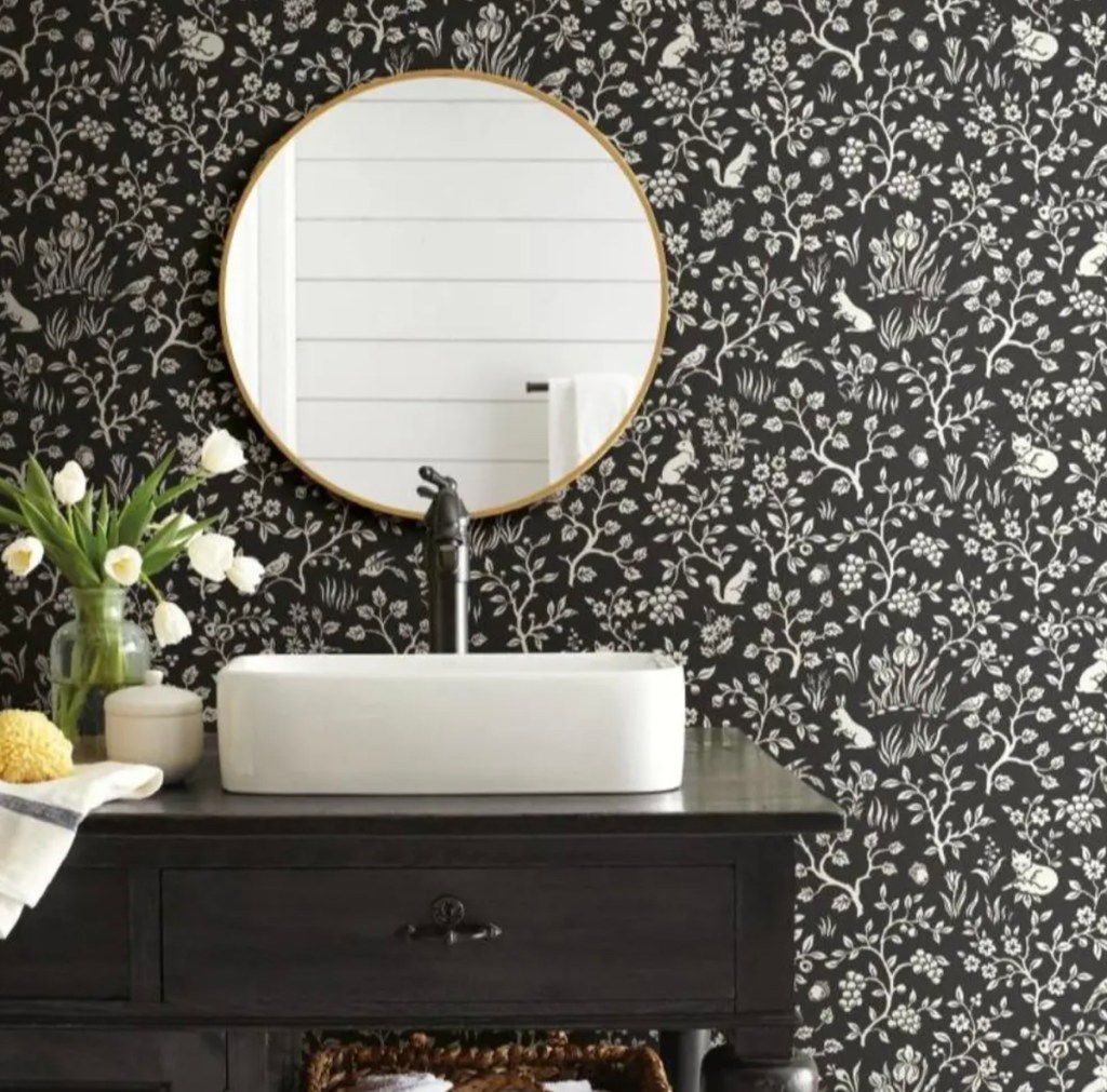 black and white fox patterned wallpaper behind mirror and bathroom sink