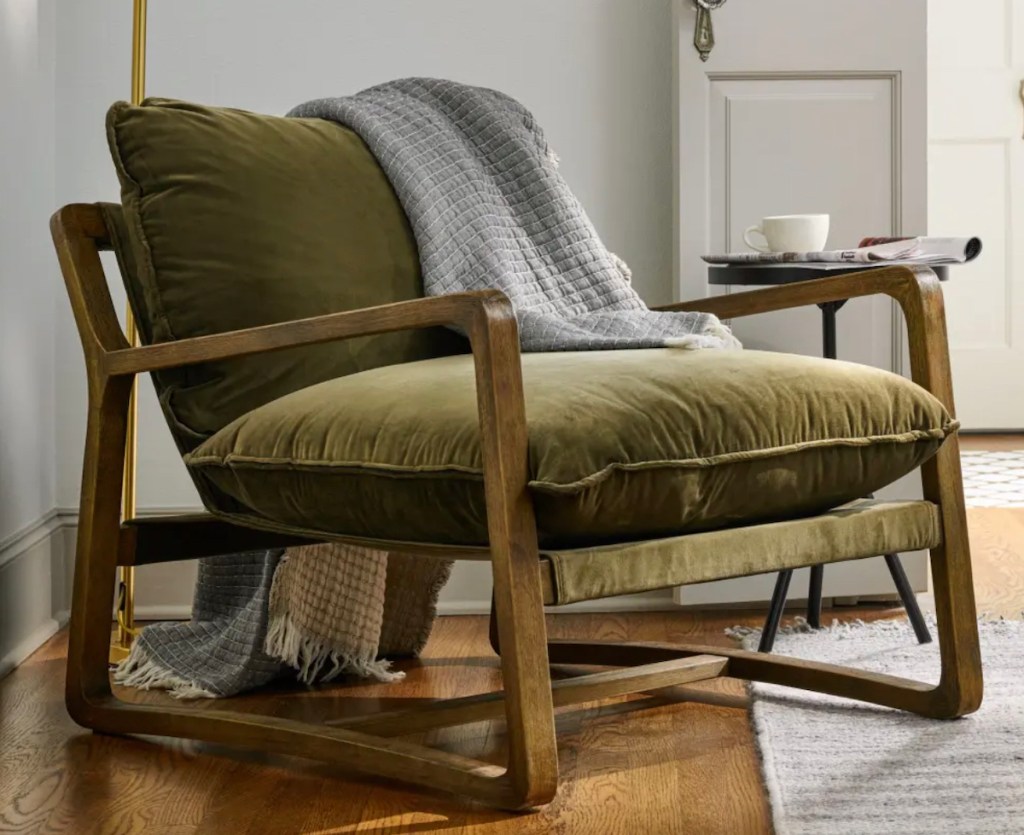 olive green velvet chair sitting in living space with gray blanket draped over top