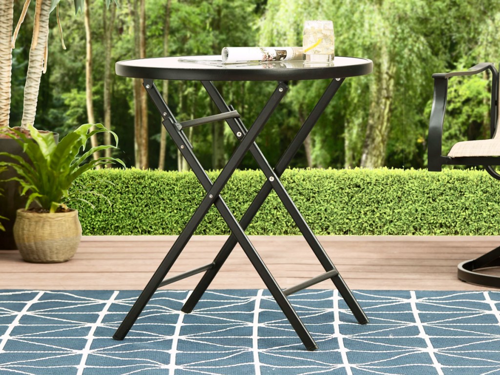 small round patio side table with drink and newspaper on top