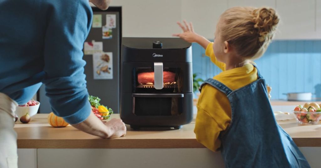 girl and man using black air fryer on counter
