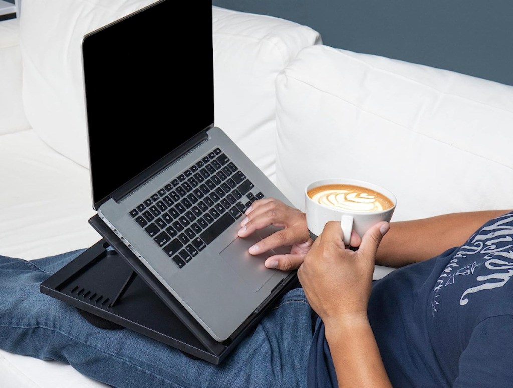 person with laptop and desk on lap sitting on white couch