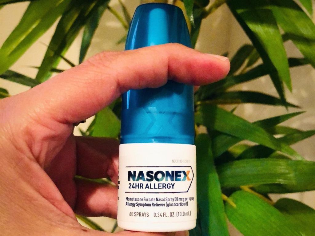 A hand holding a Nasonex 24hr bottle