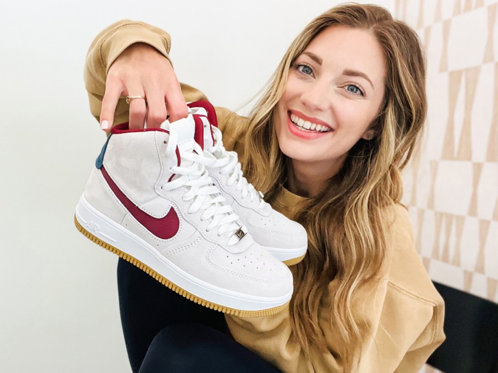 woman holding up a pair of nike sneakers
