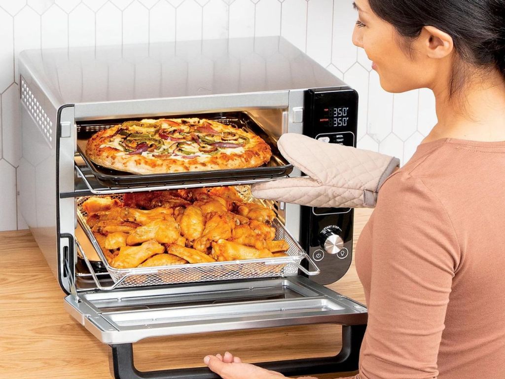 Woman getting food out of a Ninja 12-in-1 Rapid Cook & Convention Double Oven