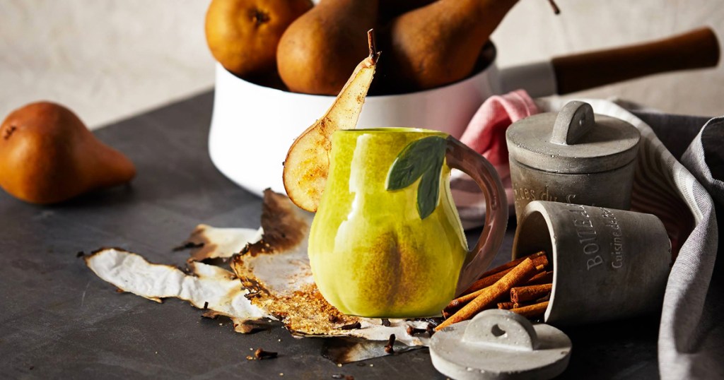 pear mug with pear slice on the rim and bowl of pears in the background