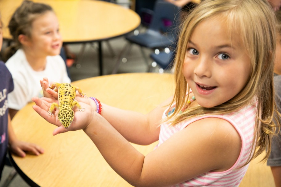 A girl holding a lizard thanks to the Pets in the Classroom program