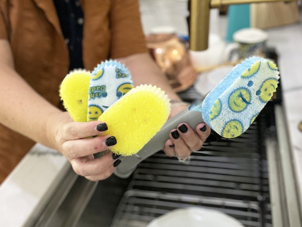 woman holding up scrub daddy dish wand and replacement sponge heads