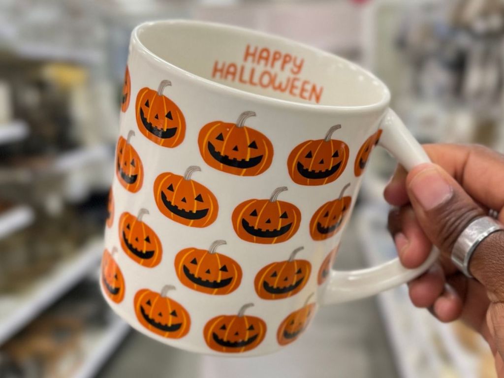Hand holding a Hallowen mug with pumpkins on it at Target