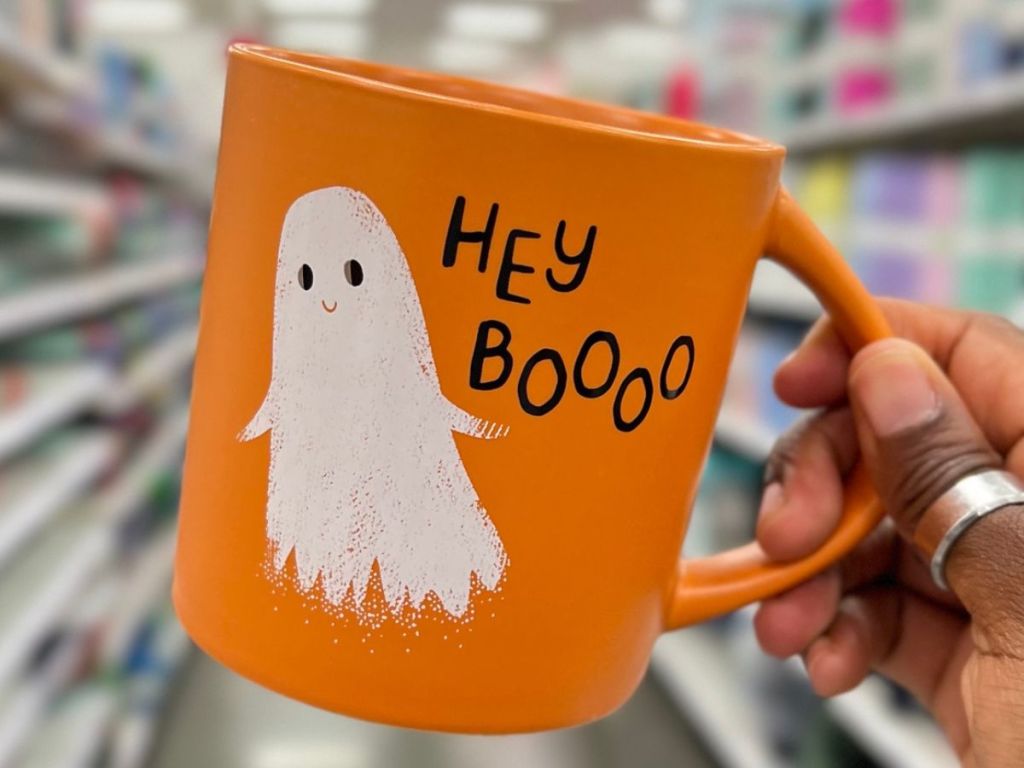 Hand holding a ghost Hey Boooo Hallowen mug at Target