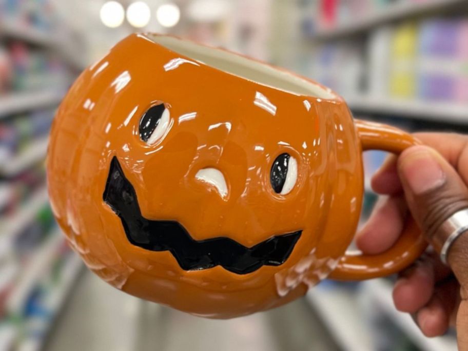 Hand holding a pumpkin shaped Hallowen mug at Target