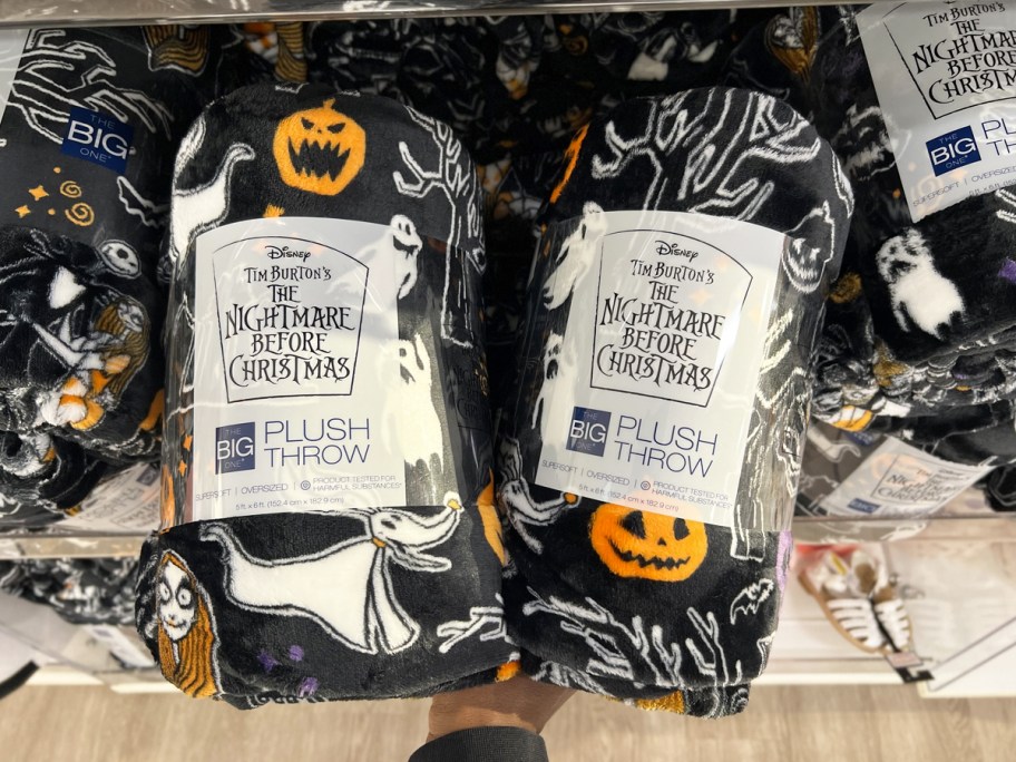 hands grabbing two black nightmare before christmas throws from shelf