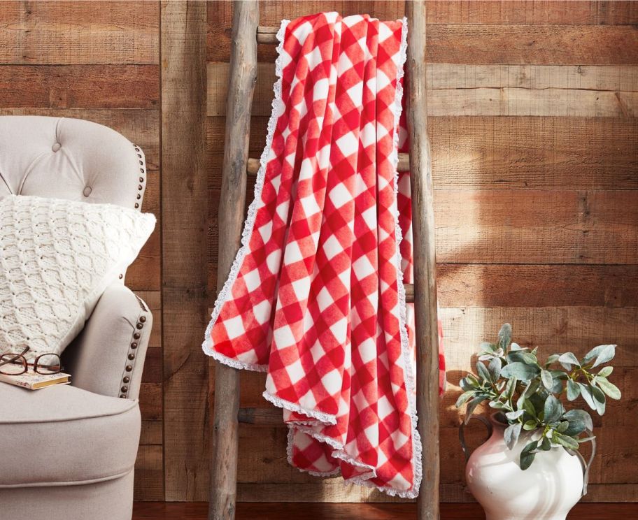 a reversible throw hanging on a rustic ladder next to a wing back chair