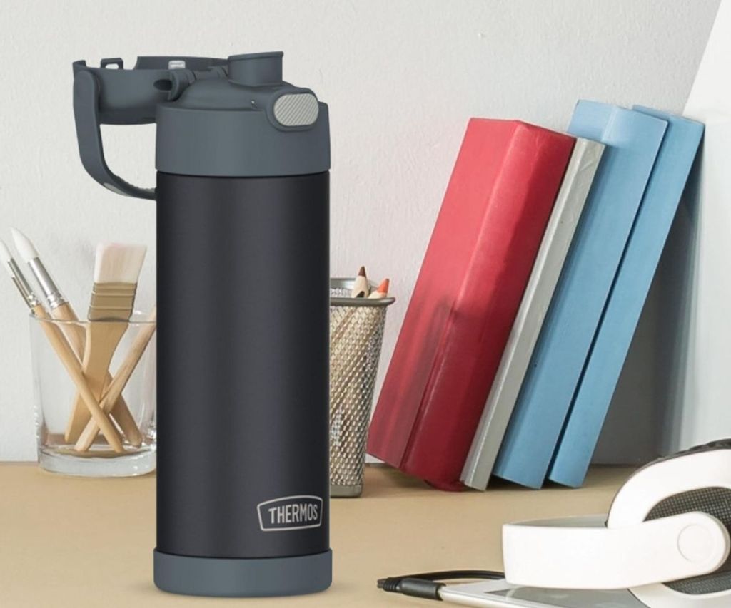 A Thermos FUNTainer on a desk with books