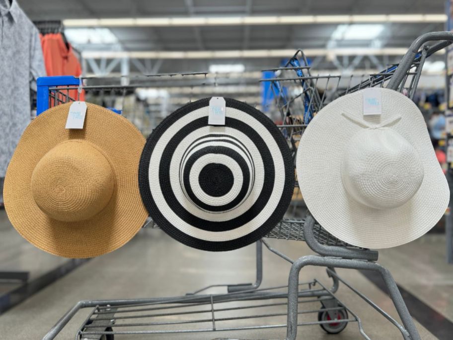 3 floppy sun hats hanging on the side of a shopping cart
