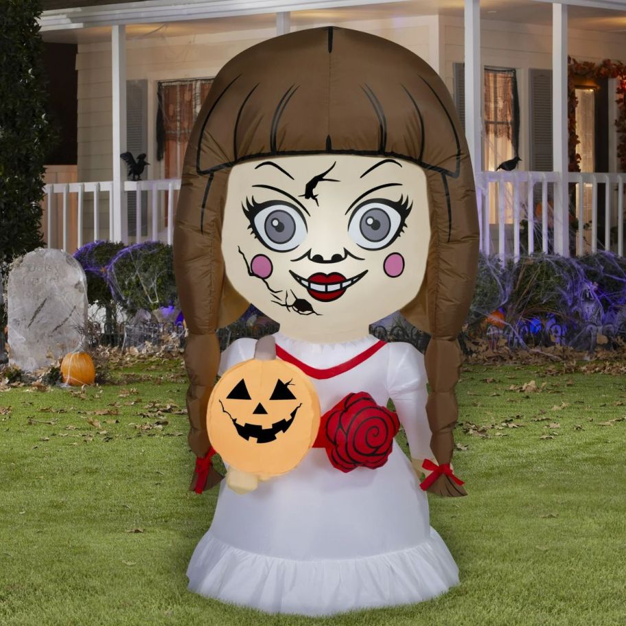 Annabelle holding a jack o'lantern halloween inflatable n front of a house.