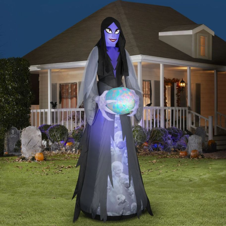 Inflatable ghoul with a glowing orb in in front of a house.