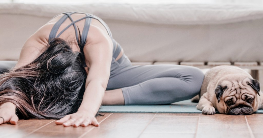 woman doing yoga at home next to dog